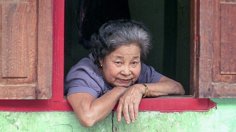 Lao Loum Frau schaut aus dem Fenster